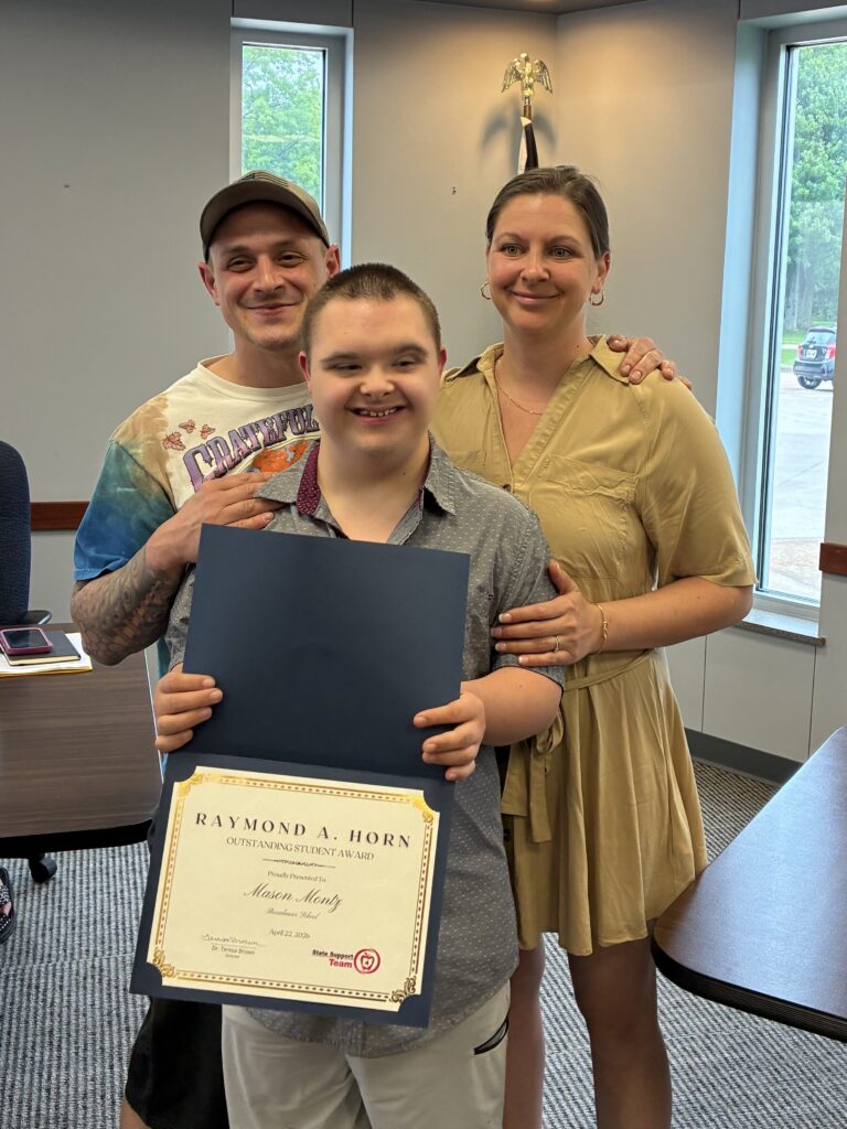 Photograph of Broadmoor student who received the Raymond A. Horn award with his parents standing closely behind him smiling and happy.